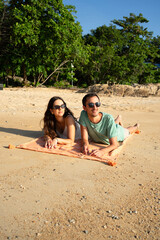 Couple relaxing on beach towel during tropical vacation