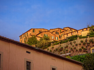 Obraz premium Old houses perch on a scenic cliff near Siena’s historic center, blending into the Tuscan landscape. A cultural travel in Italy.