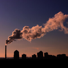 Square Stock Photo of the Cityscape and Smoke Over Buildings from a Factory Chimney At Evening
