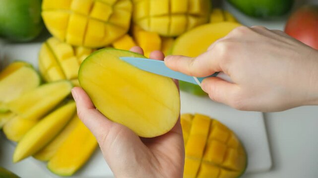 Hands Cutting Mango Half into Cubes with Knife, Close-Up