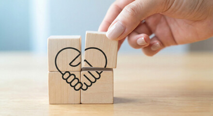 A hand carefully places the final wooden block with a handshake symbol, signifying the act of building a strong relationship.