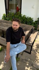 Fototapeta premium Pensive Man with Furrowed Brow Sitting at Outdoor Table, Deep in Thought