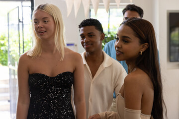 Diverse friends celebrating in decorated living room under pennant banners near glass door