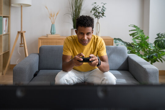 Man playing video game with controller on couch at home
