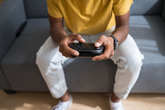 Man playing video game with controller indoors on sofa closeup
