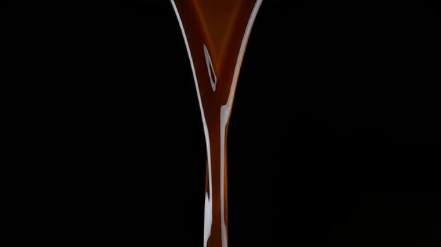 Rich Dark Chocolate Syrup Pouring Down in a Smooth, Continuous Stream Against a Black Background.