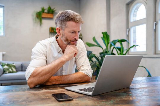 Confident professional working with laptop at home office