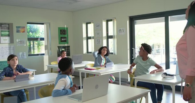 Teacher with youth students asking question in class, central girl raising hand to answer laptop
