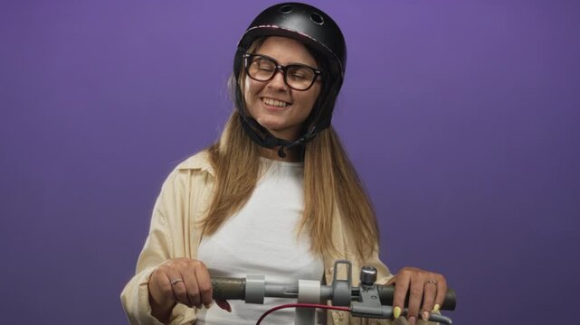 Young hispanic woman wearing helmet and glasses holding scooter handlebars and smiling with visible hands and yellow nails in a purple studio; joy carefree confidence.
