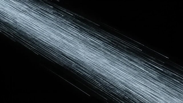 Streaks of white light move across a dark background in a dynamic motion.