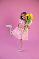 funny girl in pink dress with yellow tulips flower on pink background.