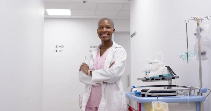 African woman in scrubs posing hospital corridor by cart IV camera closing causing smiling-laughing