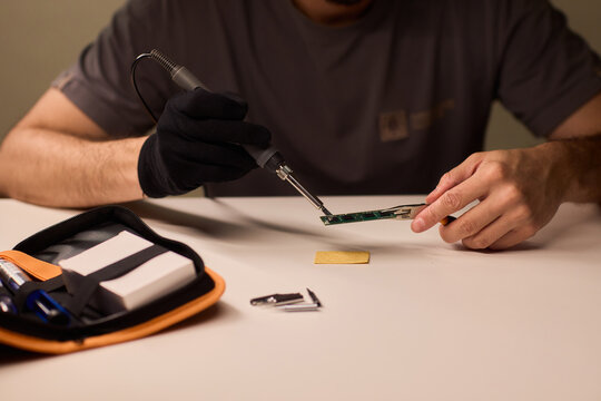 Detailed shot capturing repair process of computer memory components, Technician carefully handling SODIMM memory module while performing technical diagnostic procedures