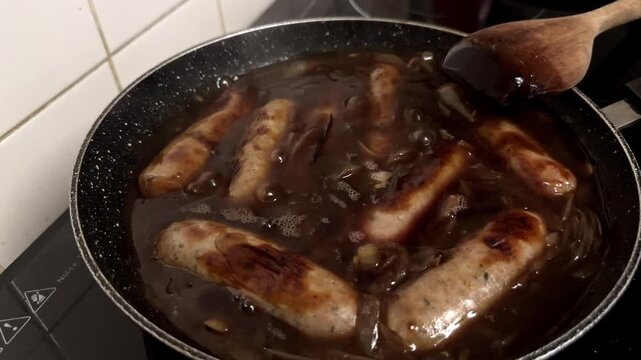 British Sausages Cooked in a Rich, Dark Caramelized Onion Gravy in a Frying Pan