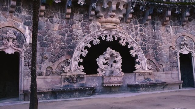 Ornate triton fountain carved into an aged stone wall creates a dark, mystical garden atmosphere, with rich textures and historic character revealed in gentle motion.