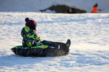 Child having fun on snow tube. Boy is riding a tubing, winter entertainment