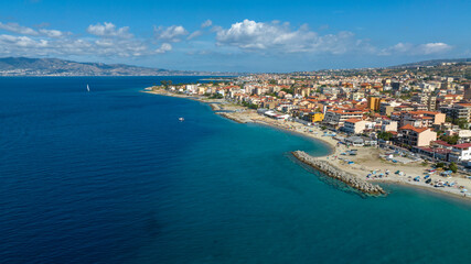 Aerial view of Gallico Beach, Calabria, Italy. It is a vibrant Mediterranean coastline. In the background, beyond the sea and the Strait of Messina, lies Sicily.