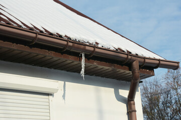 Icicle formed by leaking gutter joint causing damage to roof gutter system