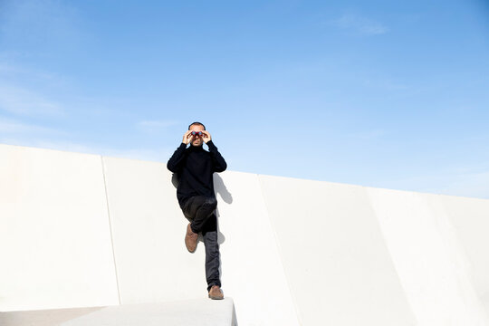 Person with binoculars observing in urban minimal setting in Barcelona