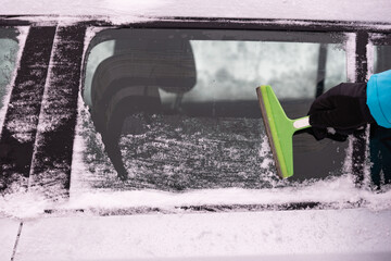 Man removes snow from car on a winter morning, outside his home in a residential area