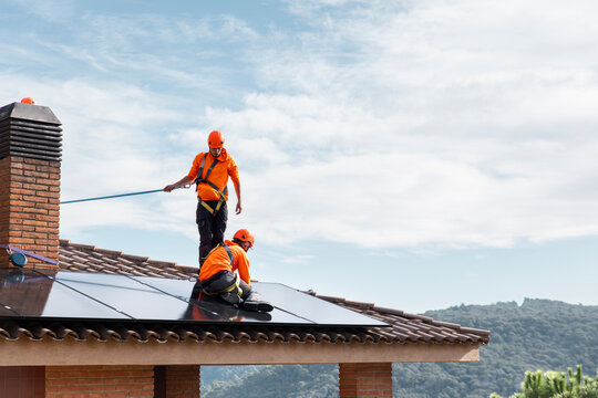 Technicians installing solar panels on a tile roof in Barcelona