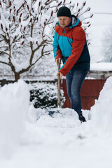 Man removes snow in the yard on a winter morning.
