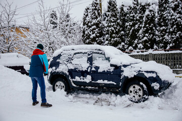 Man removes snow near car on a winter morning, outside his home in a residential area