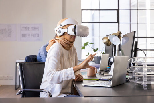 Virtual reality headset sitting on desk, with laptop, coffee, plant and sketches - Powered by Adobe