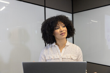 African american woman working on laptop in meeting room with whiteboard walls, chart projection