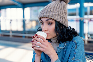 Woman enjoys warm drink while sitting in public space on a chilly day