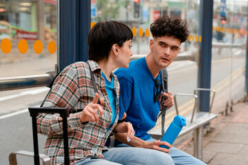 Friends talk at bus stop during afternoon in city