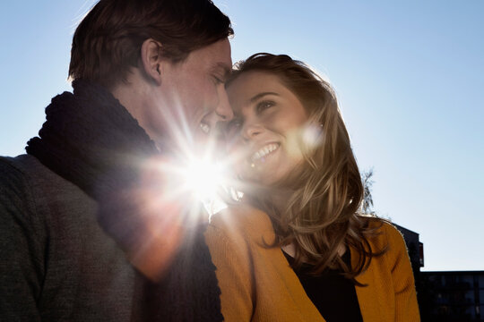 Happy couple outdoors smiling in back light with scarf and autumn clothing