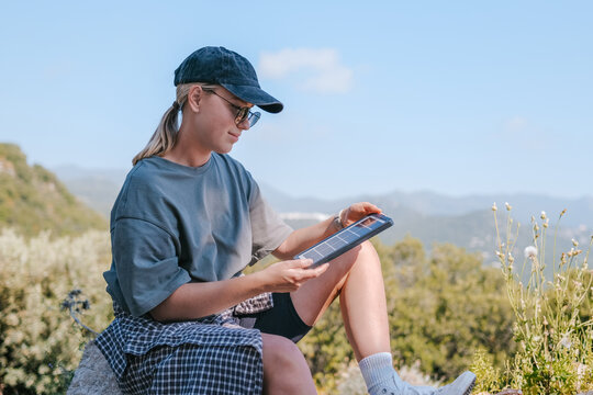 Person relaxing outdoors in mountains using portable solar panel
