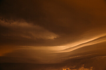 Fototapeta premium Orange yellow Cloudy Sky With Dark Storm Clouds During Rain. Natural Background With Rainclouds. natural weather background dark yellow backdrop thunderstorm stormy sky