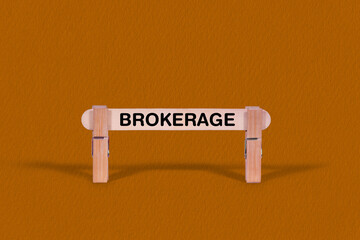 Fototapeta premium Brokerage symbol. Wooden stick tightened by Clothespins, beautiful Orange color Backdrop. Business and Brokerage concept with copy space