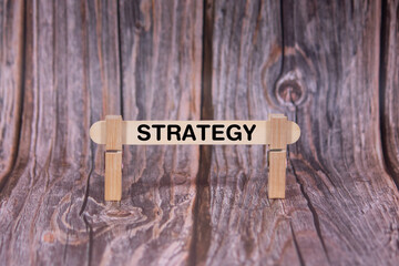 Fototapeta premium Strategy symbol. A wooden stick clasped by clothespins set over a beautiful Brown Grunge Wooden Texture Background. Business and Strategy concept with copy space