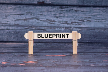 Fototapeta premium Blueprint symbol. Wooden stick fastened by Clothespins, A lightly orange toned grunge wooden background. Business and Blueprint concept with copy space