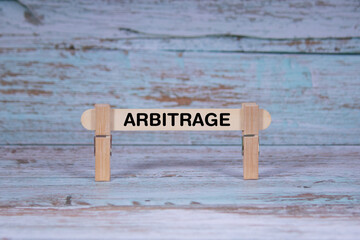 Fototapeta premium Arbitrage symbol. Single Wooden stick squeezed by Clothespins, Grungy blue Wooden Texture Background. Business and Arbitrage concept with copy space