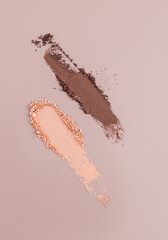 Two beautiful strokes brown and beige cosmetic dry product. The texture of an eyeshadow sample or a compact face powder on abeige vertical background.