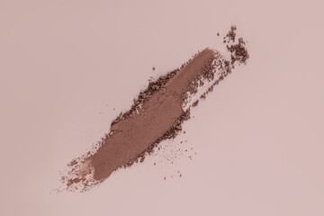 Beautiful brushstroke of brown loose eyeshadow on a beige background. top view. A copy of the space. A sample texture of decorative cosmetics.