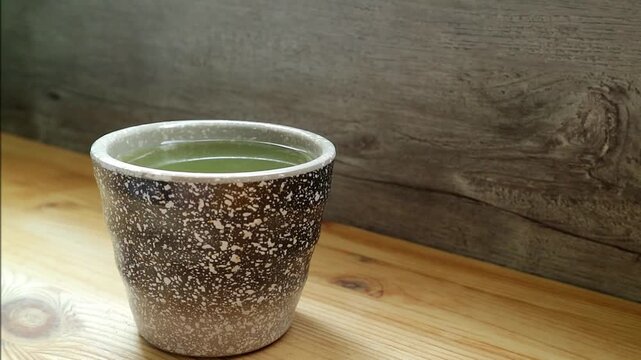 Footage of a Cup of Hot Matcha Green Tea with Water Vapor on Wooden Table