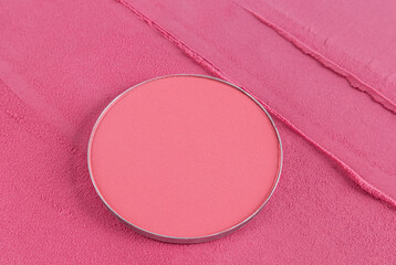 Close-up of round block or refill of pink blush on a background of soft pink blush powder. Beautiful texture of decorative cosmetics. Template.