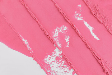 Cosmetic background texture of delicate pink blush. A sample of smears of a loose cosmetic product. top view. Straight parallel lines of blush texture
