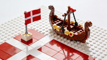 Fototapeta premium Flatlay of Denmark flag with LEGO Viking ship showcases Danish culture and creativity