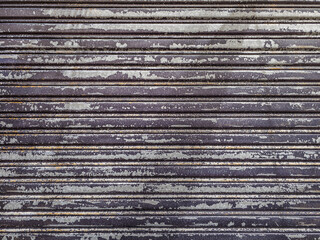 Closed metal rolling security shutter exhibits signs of aging and wear. Flat real life texture and background.