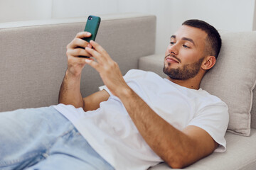 Man relaxing at home, engaging with his phone, representing digital detox and mental health awareness in a cozy environment.
