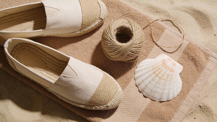 Footwear and beach items on a towel on the sand at a seaside location in the morning light