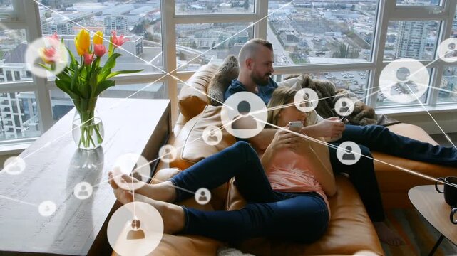 Profile icons connecting with lines over caucasian couple relaxing on couch and using smartphones