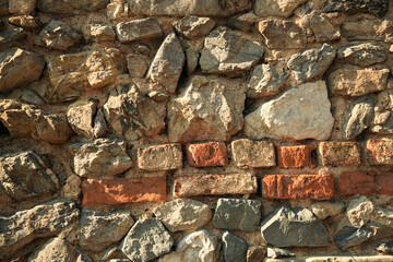 background: bricks, stones, fragment, wall. A fragment of an old brick wall of a medieval fortress.