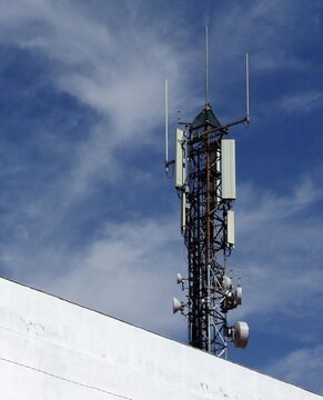 Communication tower transmitting cellular network signals on blue sky